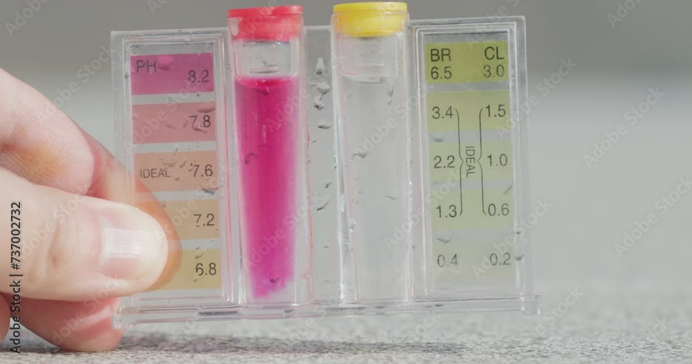 A hand holds a test tube with tests for PH and chlorine levels. A hand holds a test tube with tests for PH and chlorine levels.