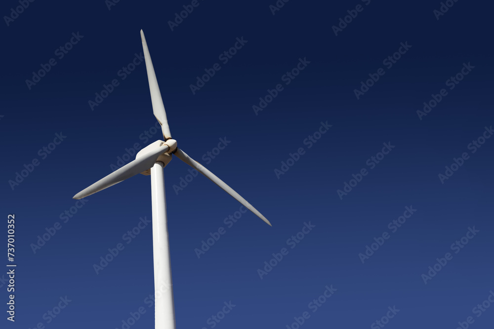 Empty copy space windmill. Green energy background. White wind turbine isolated on blue sky.