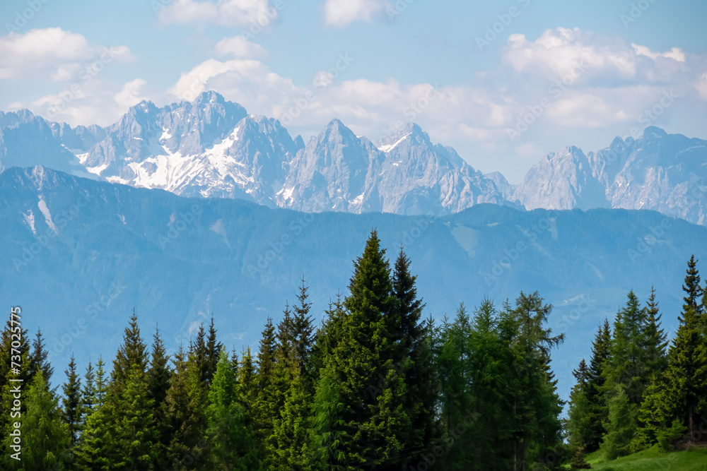 Panoramic view of untamed Julian Alps and Karawanks seen from Gerlitzen, Carinthia, Austria. Looking at majestic mountain peak Spik and Skrlatica. Wanderlust Austrian Alps in summer. Idyllic forest