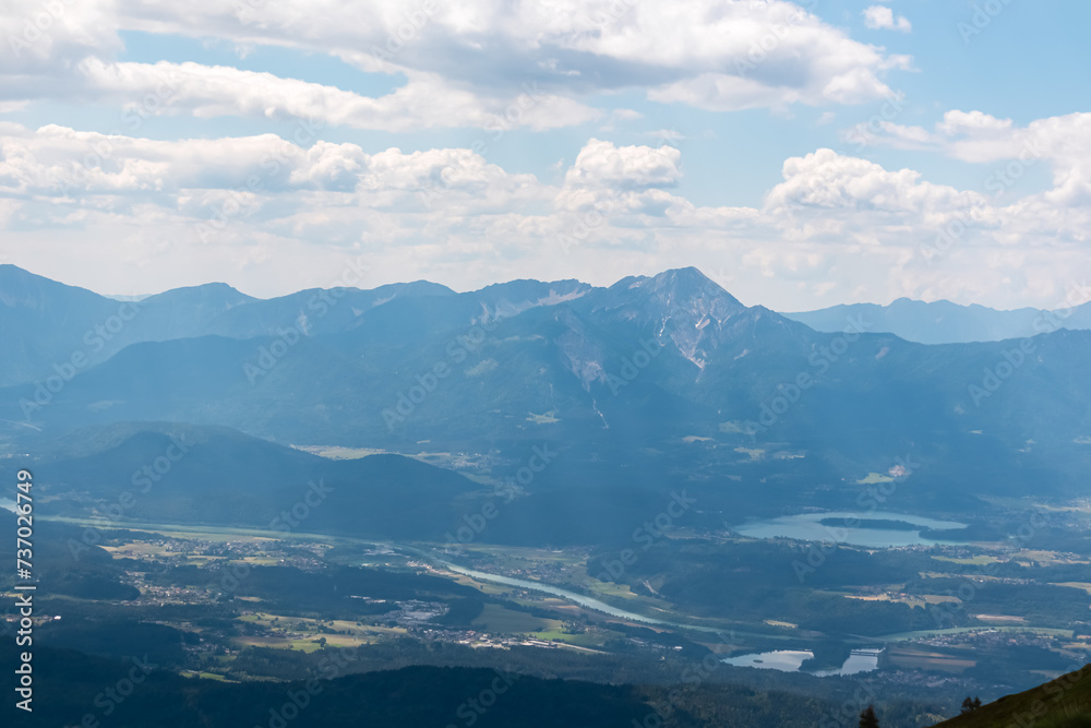 Panoramic view of Lake Faak surrounded by majestic mountain peaks of Karawanks and Julian Alps. Wanderlust on Gerlitzen Alpe,  Carinthia, Austria. Idyllic hiking trail in Austrian Alps in summer
