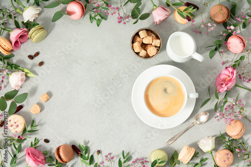 White cup of coffee and Frame made of Spring flowers and different types of macaroons