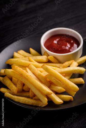 French fries with tomato sauce. on a black wooden background.