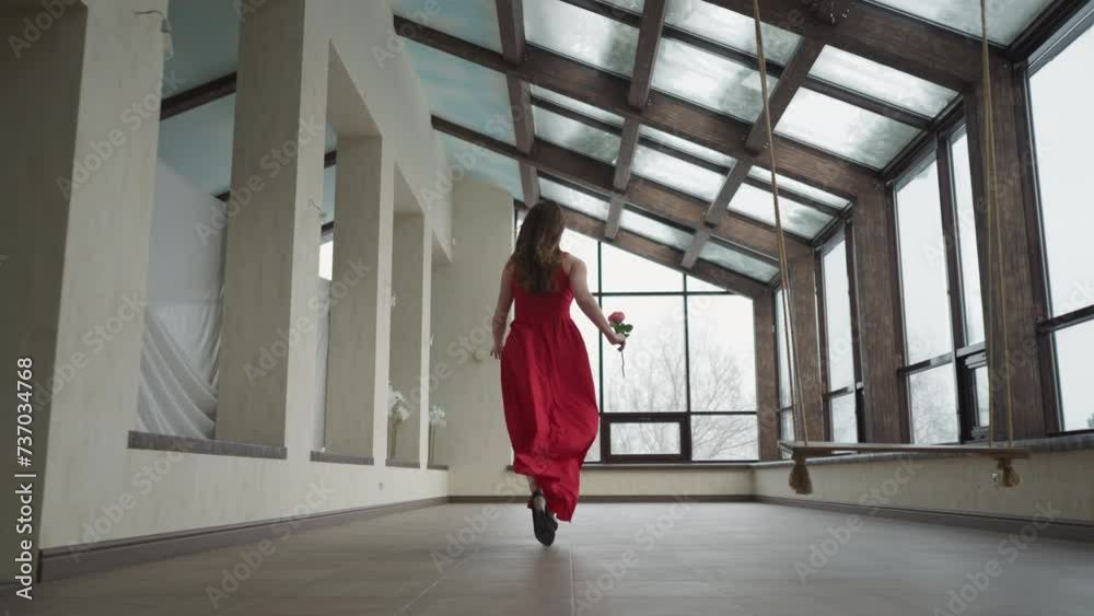Model in waving dress swiftly approaches window. Young woman creates visually arresting moment in motion in art gallery. Striking contrast against surroundings Model in waving dress swiftly approaches window. Young woman creates visually arresting moment in motion in art gallery. Striking contrast against surroundings