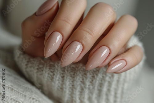 Closeup to woman hands with elegant neutral colors manicure. Beautiful nude manicure on long almond shaped nails. Nude shade nail manicure with gel polish at luxury beauty salon