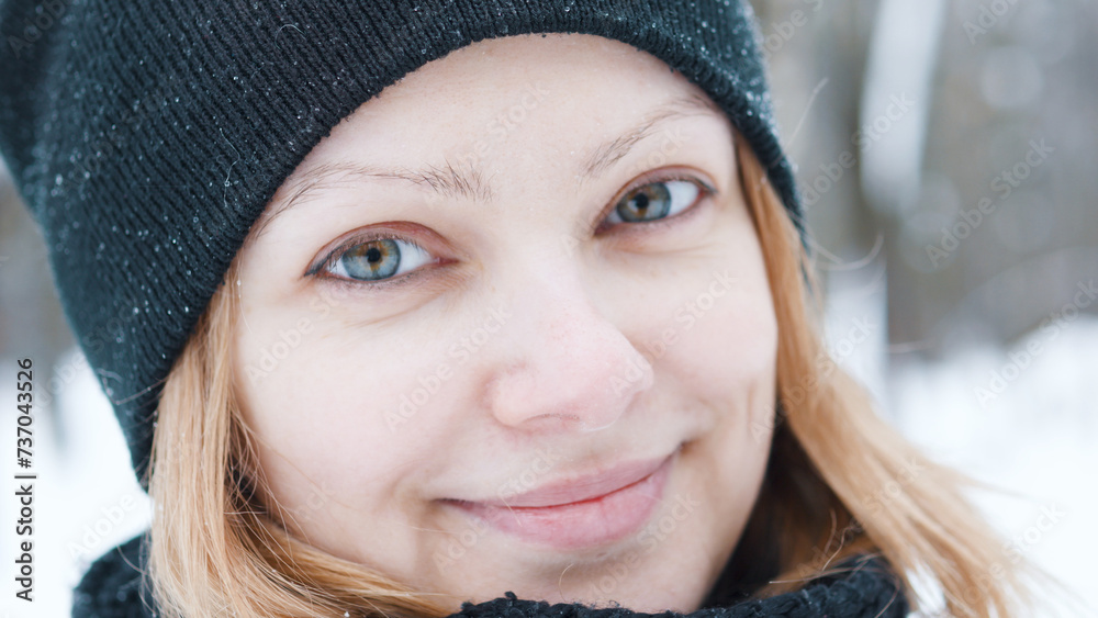 Portrait of beautiful smiling winter girl in black hat looking at camera.