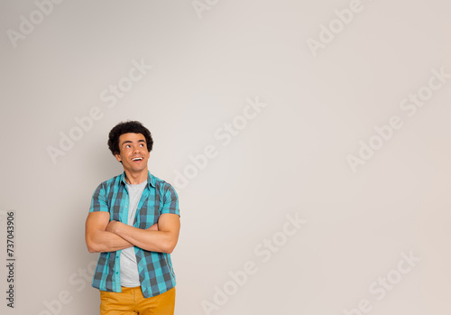 Successful young businessman with arms crossed looking away and contemplating on white background