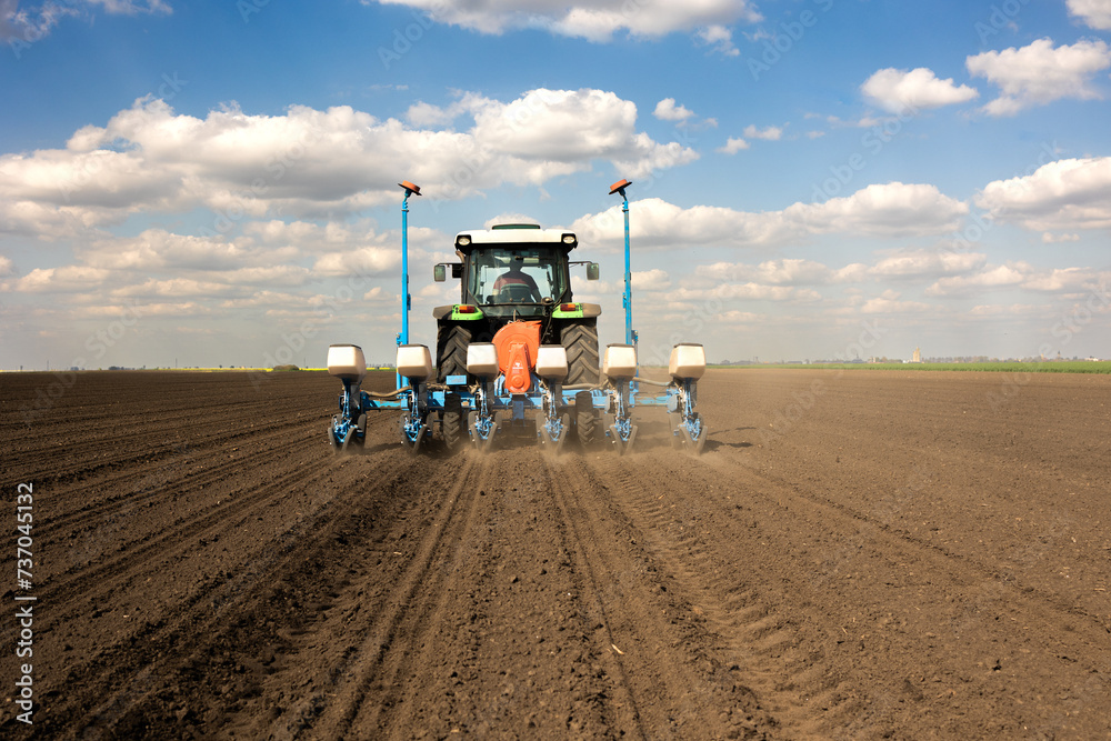 Fototapeta premium Farmer with tractor seeding crops at field