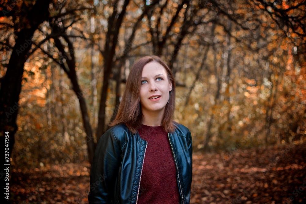 A young ginger girl portrait standing in the autumn park next to autumn tree A young ginger girl portrait standing in the autumn park next to autumn tree