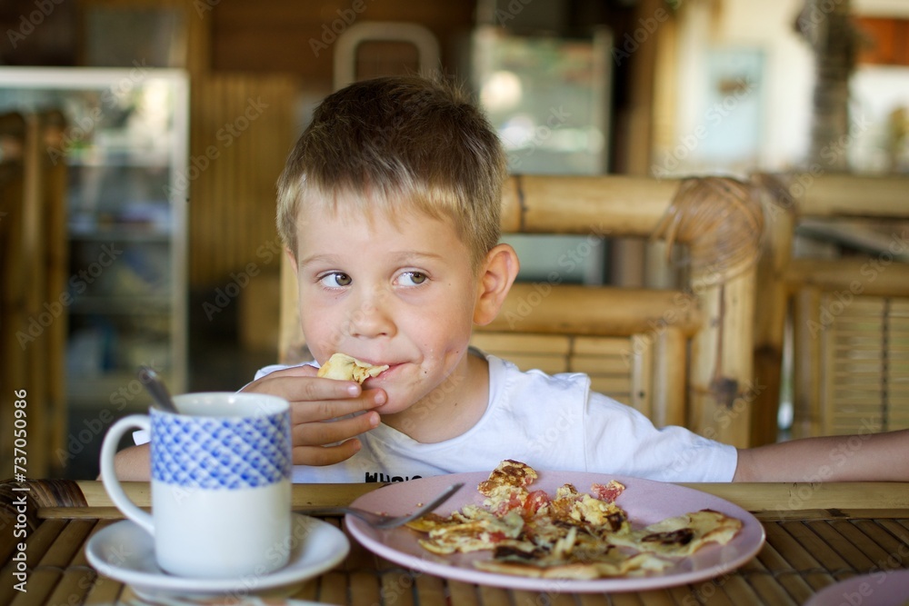 Young caucasian boy eating a toast with jam for the summer breakfast sitting outside Young caucasian boy eating a toast with jam for the summer breakfast sitting outside