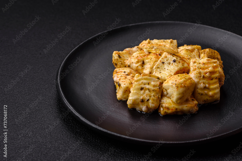 Delicious soft white feta cheese with salt, spices and herbs on a dark concrete background