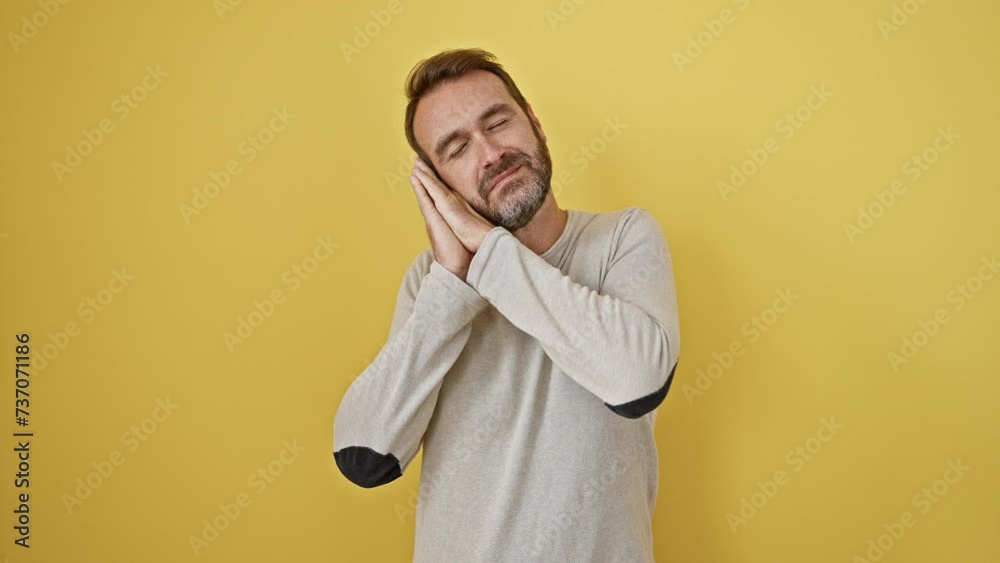 Sleepy hispanic man dreaming while standing, hands together, smiling with eyes closed, posing on yellow isolated background Sleepy hispanic man dreaming while standing, hands together, smiling with eyes closed, posing on yellow isolated background