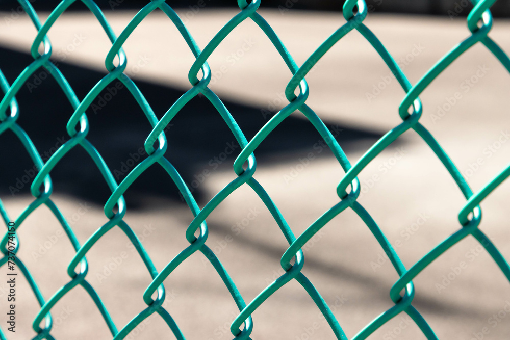 Close-up green metal chain link fence with blurred background