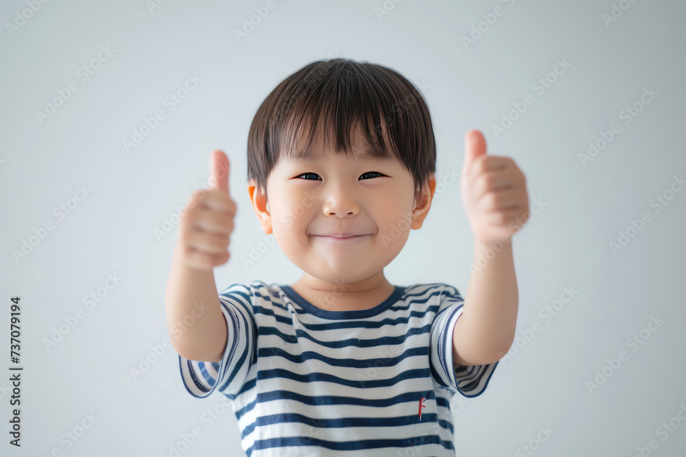 Happy little cute Asian boy giving thumbs up on white background Happy little cute Asian boy giving thumbs up on white background