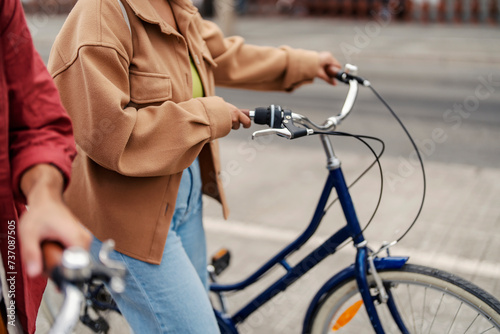 Cropped picture of a girl walking on a street and pushing bicycle. © dusanpetkovic1