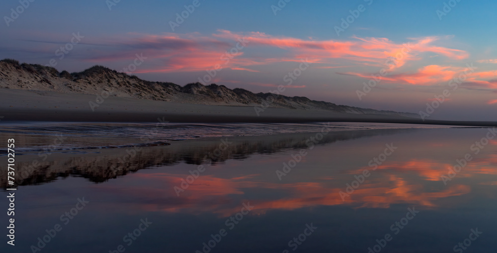 Sunset landscape of the Viago beach in Pedrogao, Figueira da Foz, Portugal, with the clouds reflected on the water.