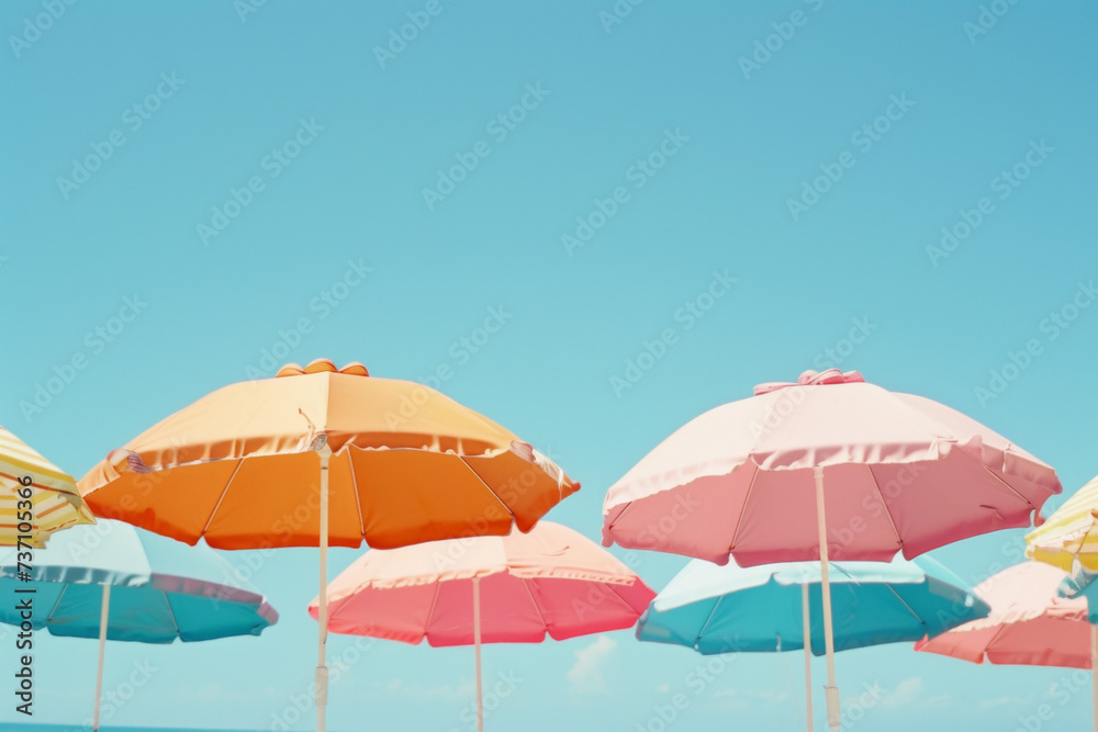 Sunny summer composition in bright pastel colors. Parasols on a beach with a clear blue sky in the background.
