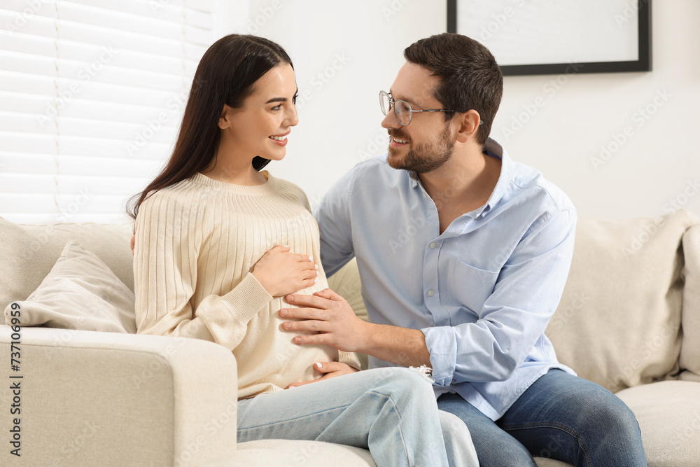Happy pregnant woman spending time with her husband on sofa at home Happy pregnant woman spending time with her husband on sofa at home