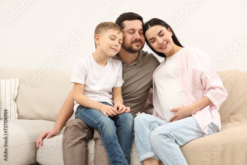 Happy pregnant woman spending time with her son and husband at home