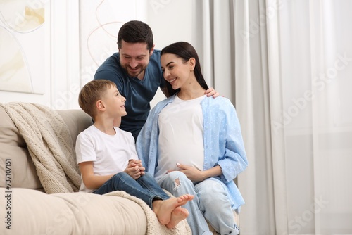 Pregnant woman spending time with her son and husband at home, space for text. Happy family