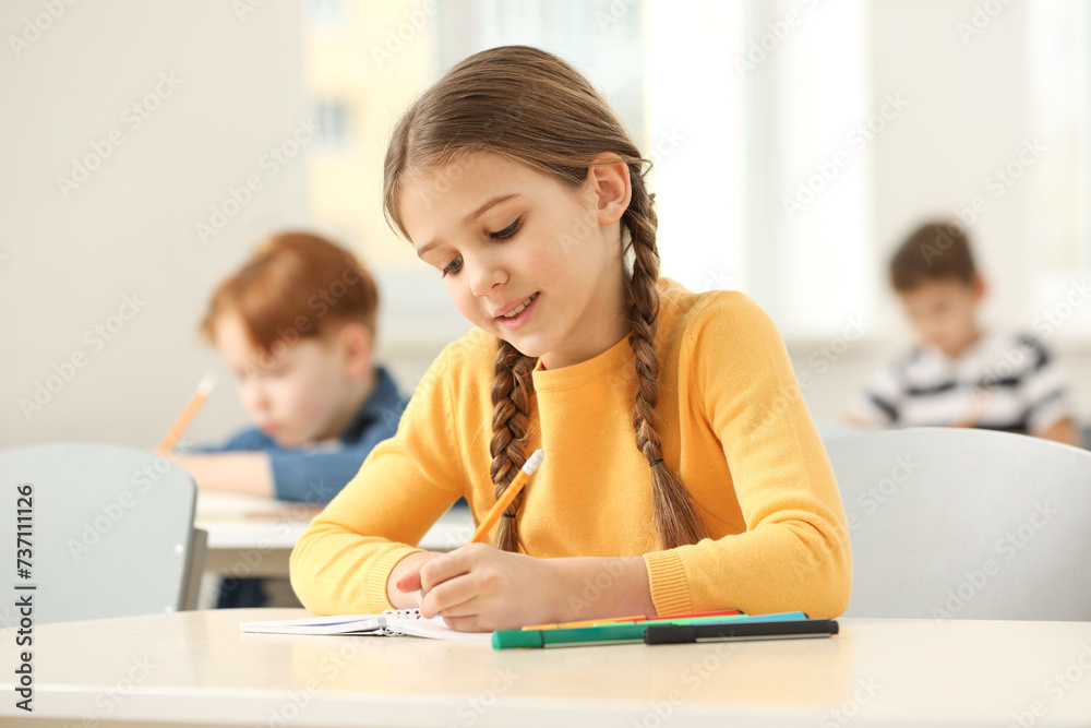 Smiling little girl studying in classroom at school Smiling little girl studying in classroom at school