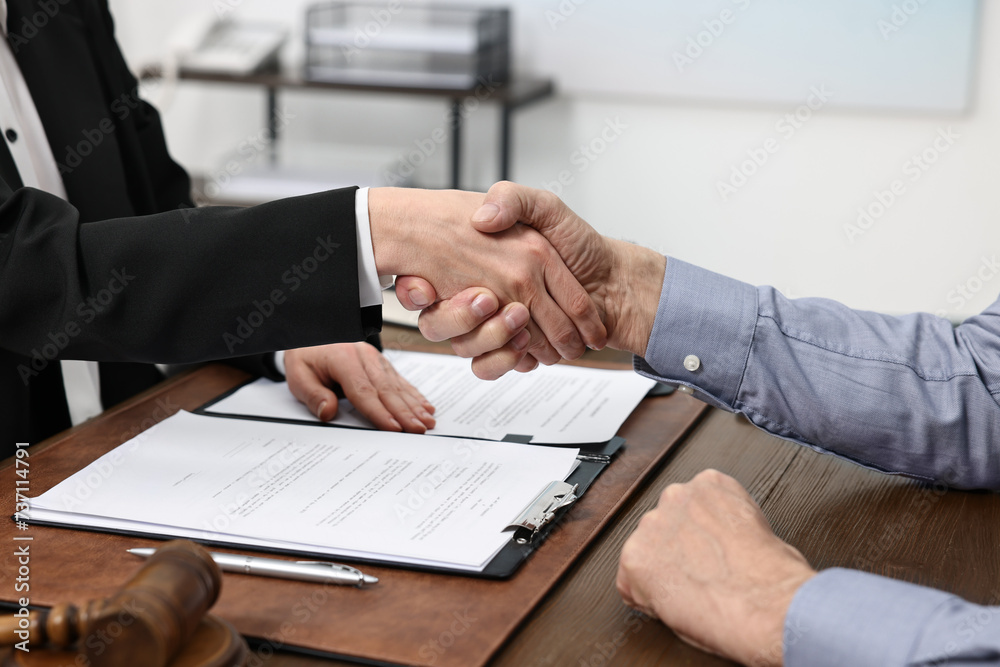 Lawyer shaking hands with client in office, closeup Lawyer shaking hands with client in office, closeup