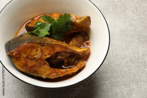 Tasty fish curry on light grey table, closeup. Space for text. Indian cuisine photo