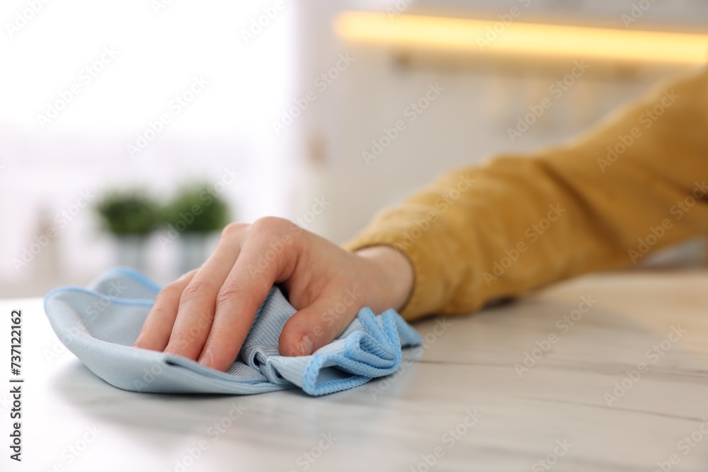 Woman with microfiber cloth cleaning white marble table in kitchen, closeup Woman with microfiber cloth cleaning white marble table in kitchen, closeup