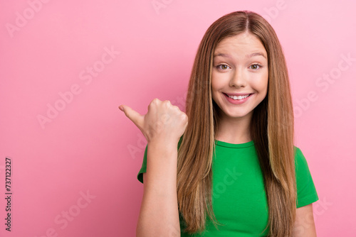 Photo portrait of charming teen girl point empty space banner promo dressed stylish green clothes isolated on pink color background