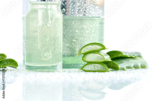Fresh Aloe vera with aloe vera extract in glass container and water droplets on white background. Natural cosmetics concept. For Health and beauty products.