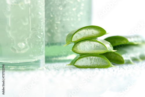 Aloe vera slices with aloe vera extract in glass container and water droplets on white background. Natural cosmetics concept. For Health and beauty products.