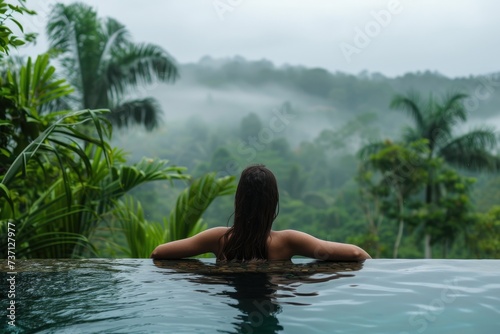 Tranquil Retreat: Young Woman Swimming in Resort Pool Overlooking Lush Mountain Vistas © Murda