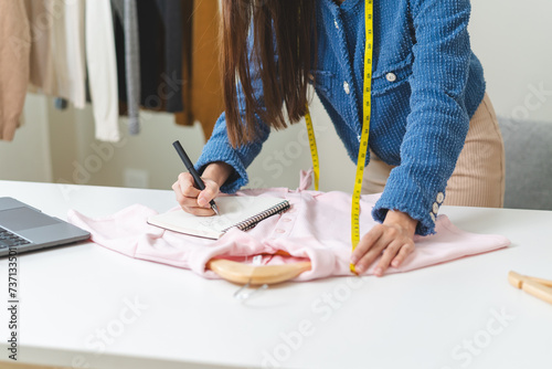 Young small business woman prepare used clothes to sell on internet. photo