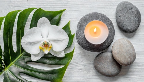 spa stones palm leaves flower white orchid candle and zen like grey stones on white background flat lay top view