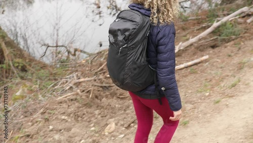 Curly and blonde hair, mountaineer woman and her dog walking through the mountains., side and back view