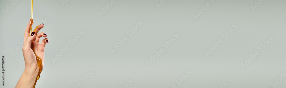 Φωτογραφία hand of unknown female with nail polish covered with natural sweet honey on gray
