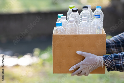 Close-up of a young volunteer collecting plastic bottles into a bin for recycling. The concept of loving the world and the environment