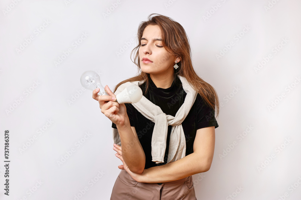 A beautiful girl is thinking about replacing an incandescent lamp with an LED one. A beautiful girl is thinking about replacing an incandescent lamp with an LED one.