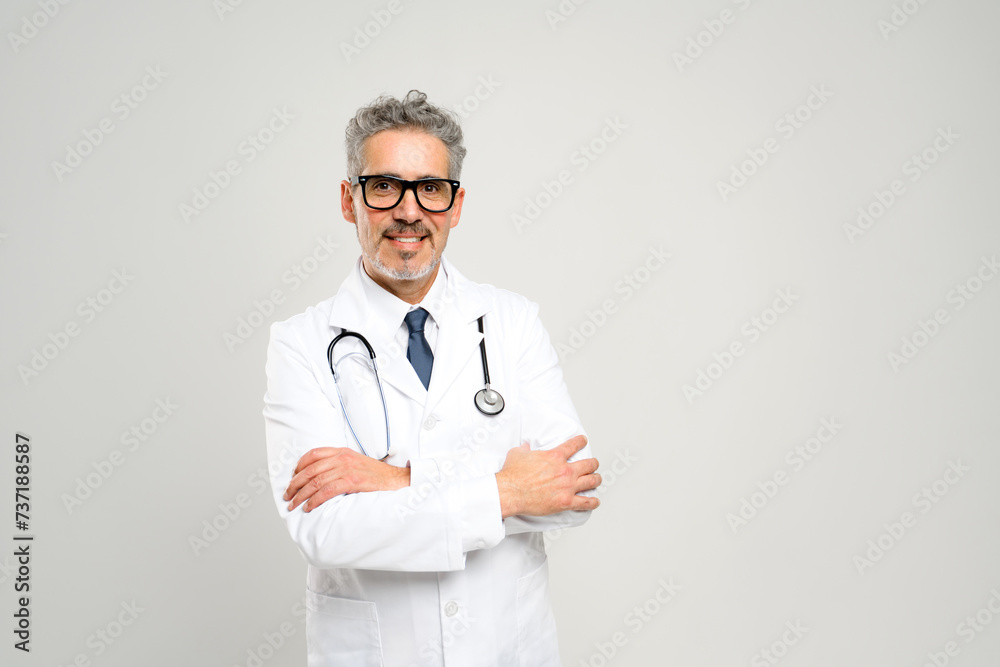 With a friendly smile and a professional demeanor, this senior doctor exudes approachability and experience, standing ready in a white lab coat with a stethoscope against a clean, white backdrop. With a friendly smile and a professional demeanor, this senior doctor exudes approachability and experience, standing ready in a white lab coat with a stethoscope against a clean, white backdrop.