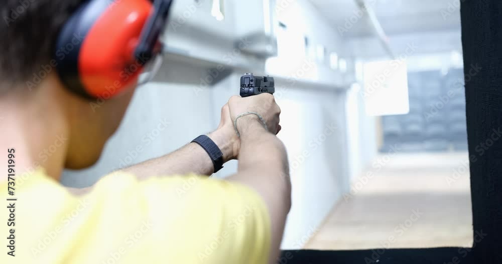 Man shoots a pistol at target in indoor range. Gun shooting training concept Man shoots a pistol at target in indoor range. Gun shooting training concept