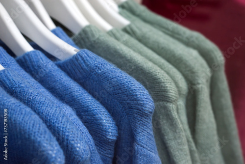 closeup of colorful woolen pullover on hangers in a woman fashion store showroom	