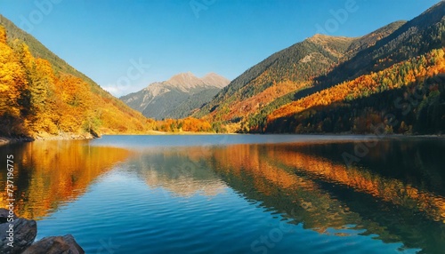 mountainous autumn landscape with lake in evening light scenery in fall colors reflecting in the calm water local tourism and relaxation concept