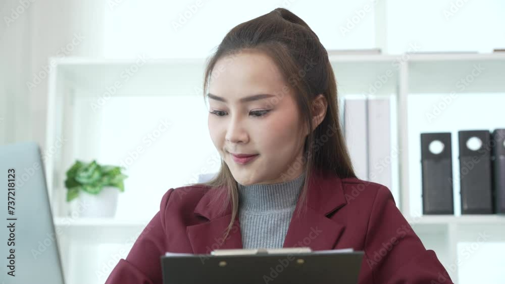 young Asian businesswoman in formal suit conducting annual audit, reviewing balance sheets, managing private offerings. works diligently at desk in professional office setting. young Asian businesswoman in formal suit conducting annual audit, reviewing balance sheets, managing private offerings. works diligently at desk in professional office setting.
