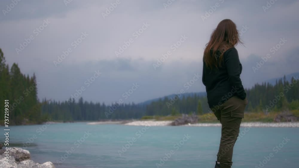 Woman standing near the river shore and looking ahead. Slow motion. Woman standing near the river shore and looking ahead. Slow motion.