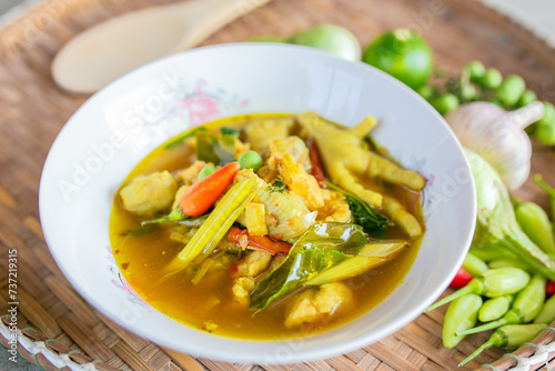 Thai green curry with chciken and vegetables in white bowl on wooden table.