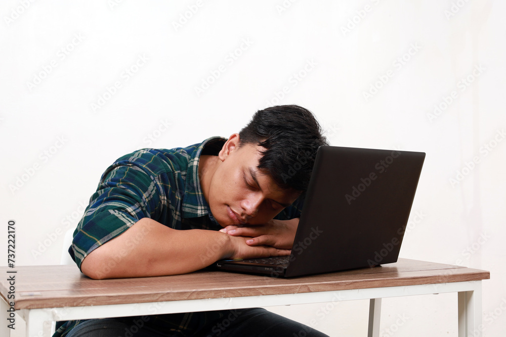 Tired young asian man sleeping while sitting with laptop on the desk Tired young asian man sleeping while sitting with laptop on the desk
