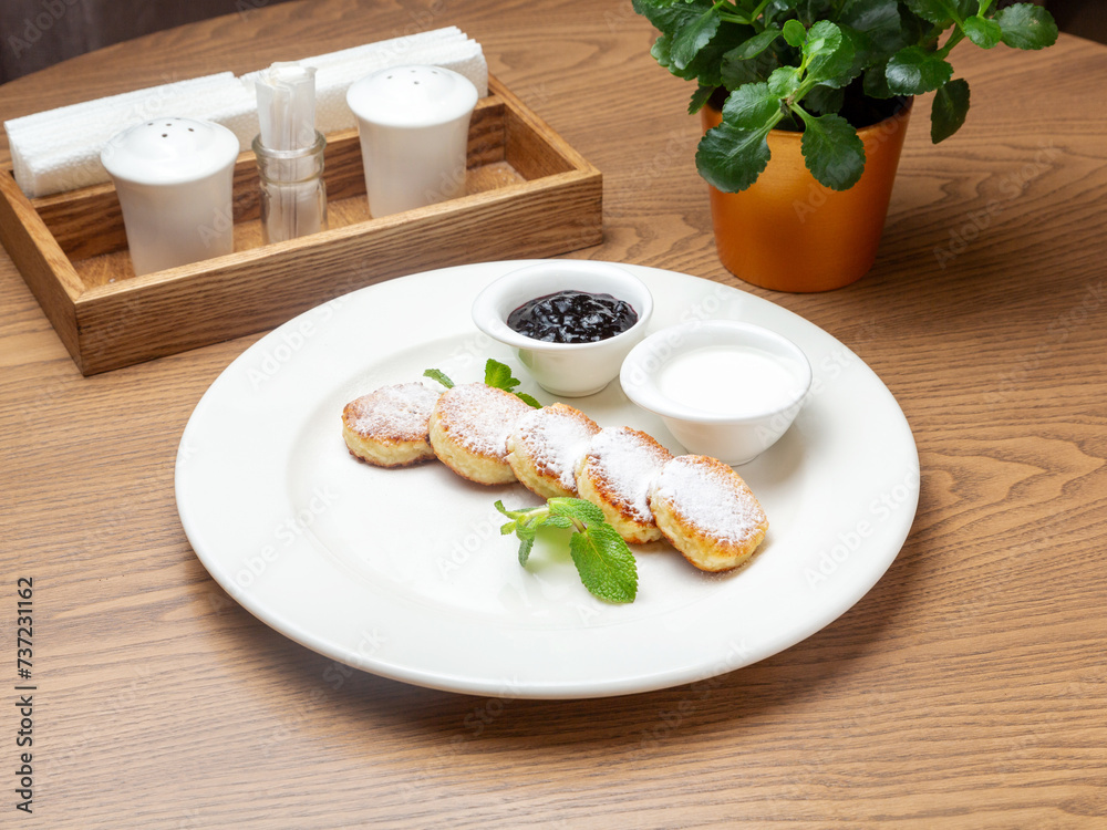 Curd cheesecakes with sour cream and jam in a plate. Lunch.