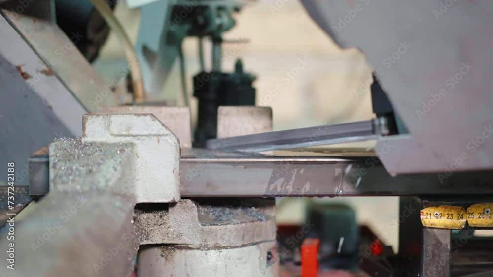 Hard work with metal on industrial factory, automated cutting machine with sharp saw and water cooling system in workshop, blade cutting metal plank with rotating motion and pressure, work with iron Hard work with metal on industrial factory, automated cutting machine with sharp saw and water cooling system in workshop, blade cutting metal plank with rotating motion and pressure, work with iron