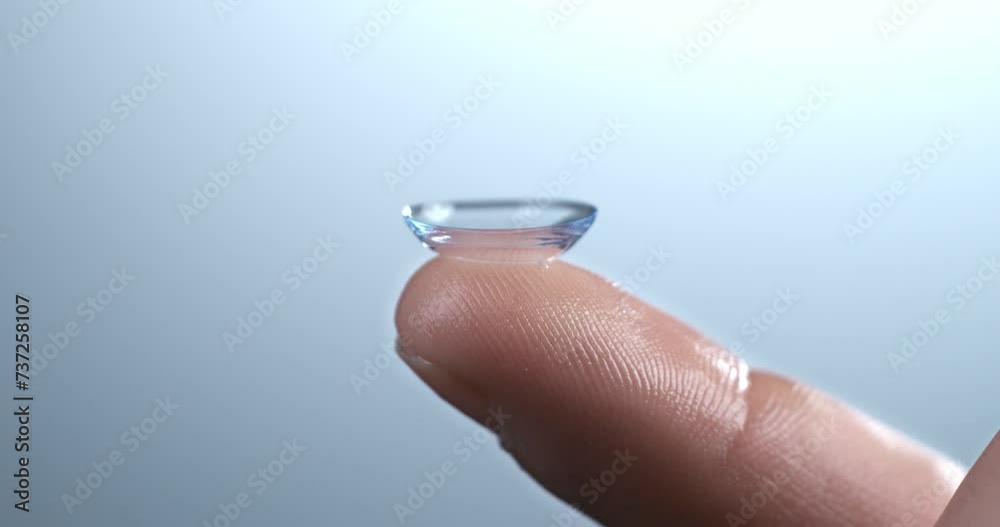 Super slow motion of drop of liquid solution for clean and disinfect is falling on contact eye ophthalmology optometry care optical lens kept on finger isolated on soft background at 1000 fps. Super slow motion of drop of liquid solution for clean and disinfect is falling on contact eye ophthalmology optometry care optical lens kept on finger isolated on soft background at 1000 fps.