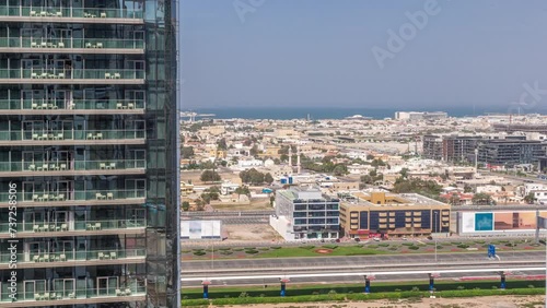 Aerial view to Dubai City Walk district viewed behind skyscraper timelapse with shadows moving fast. Low rise buildings and villas created as European-style. Traffic on the sheikh zayed road and metro photo