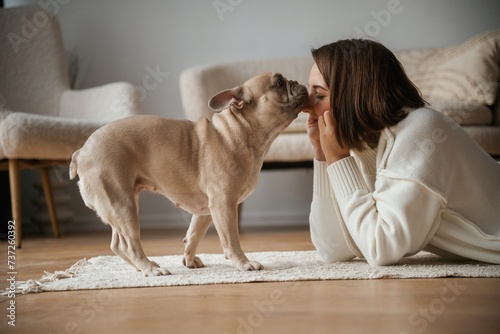 Looking at each other, lying down on floor. Young woman is with her pug dog at home © standret